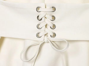 Detailed view of cream dress featuring metal eyelets and cross-lacing with a bow tie