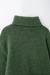 Dettaglio ravvicinato di un maglione in mohair verde scuro con collo alto lavorato