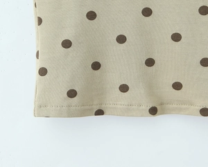 Détail du tissu kaki à pois avec une double surpiqûre précise sur l'ourlet de la jupe