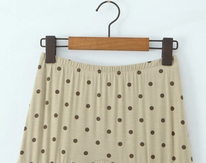 Vue détaillée d'une jupe kaki à pois avec taille élastique sur un cintre en bois