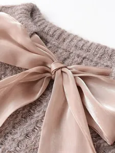 Detail of soft knit sweater featuring a large satin bow accent on the neckline