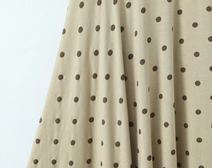 Vue détaillée du tissu beige doux avec pois brun foncé et drapé fluide naturel