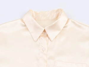 Close-up of champagne satin blouse showing premium lapel collar and silk-like texture
