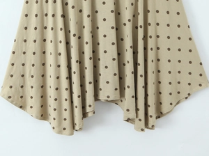 Détail de la jupe kaki à pois montrant l'ourlet irrégulier drapé et le tissu léger