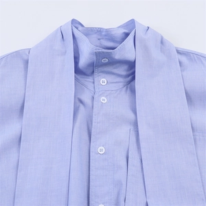 Light blue high neck shirt with white buttons and decorative bow straps at the neckline