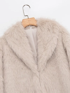 Close-up of fluffy faux fur texture and lapel collar of the cream winter jacket