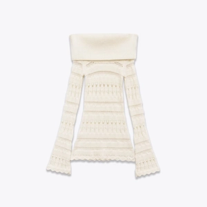Detail of white off-shoulder knit sweater showing intricate wave pattern and lace-up texture