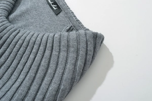 Close-up detail of grey ribbed knit neckline and brand label on a long sleeve dress