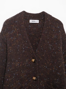 Gros plan du cardigan tricoté à col en V avec texture mouchetée et boutons ambrés