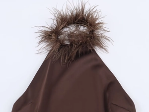 Detail of brown halter neckline featuring plush feather trim and smooth satin fabric finish
