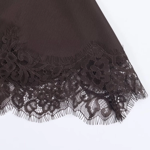 Detailed close-up of chocolate satin dress hem featuring exquisite rose lace and eyelash fringe