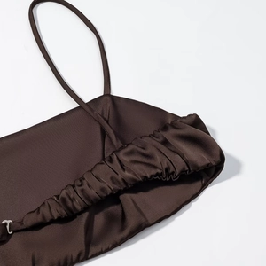 Detail eines dunkelbraunen Satin-Kleides mit Spaghettiträgern und Raffung