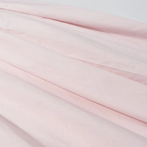 Gros plan sur la texture du tissu rose clair avec drapé naturel et détails plissés