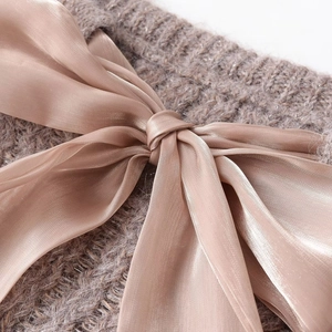 Minimalist knit sweater featuring a large satin ribbon bow in earth brown tones