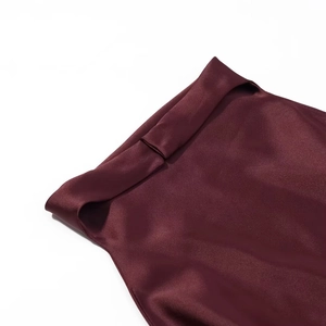 Détail de robe en satin bordeaux montrant la couture de taille et la texture soyeuse lisse
