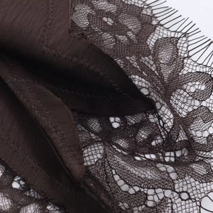 Detail of delicate floral lace trim and satin stitching on a dark brown dress
