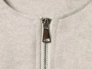 Détail de la fermeture éclair en métal argenté et du tissu en laine sur la veste