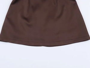 Detailed close-up of dark brown dress hem featuring precise stitching and smooth fabric