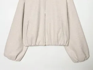 Détail de la veste aviateur beige montrant la texture laineuse et la fermeture éclair en métal