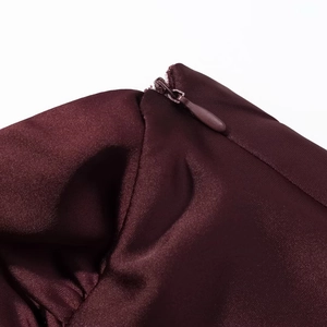 Détail de la fermeture éclair invisible sur une robe en satin bordeaux aux coutures nettes