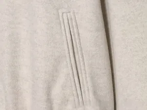 Détail macro de la texture du tissu en laine et poche passepoilée sur la veste beige