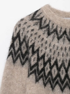 Close-up of beige knit sweater with black geometric patterns and fuzzy mohair texture