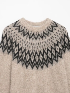 Close-up of beige knit sweater showing Fair Isle geometric jacquard and wool texture