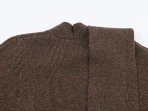 Détail du tissu en maille de laine marron foncé avec col montant et texture superposée