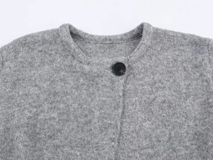 Detail of gray knitted cardigan neckline with a round neck and single black button