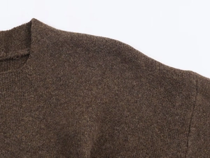 Gros plan du pull en maille marron foncé montrant la texture laineuse et les coutures d'épaule