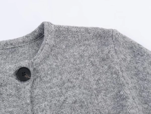 Macro shot of grey knit cardigan showing wool texture, round neck and black button detail