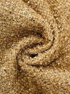 Macro detail of luxury gold metallic tweed fabric with intricate woven textures for winter jackets