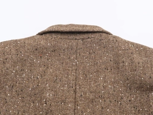 Détail de la texture en tweed marron à chevrons sur le revers et l'épaule d'un blazer