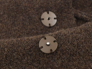 Gros plan sur un tricot marron épais avec bouton-pression rond en métal bronzé