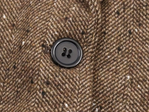 Gros plan de la texture en tweed à chevrons marron avec un bouton en résine noire