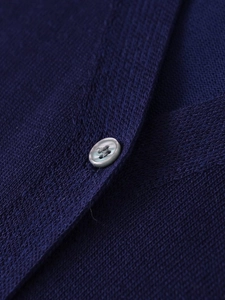 Detailed macro view of gray buttons and fine knitted texture on navy blue V-neck cardigan