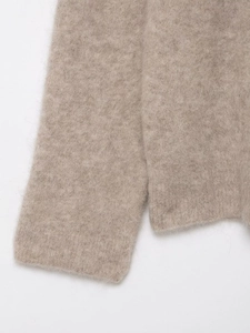 Detailed close-up of light brown knit sweater sleeve showing soft fuzzy wool texture