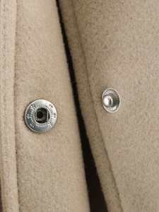 Macro detail of silver metal snap buttons on a khaki wool blend textured jacket
