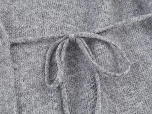 Detailed texture of gray knit cardigan featuring a soft tie belt and wool fabric finish