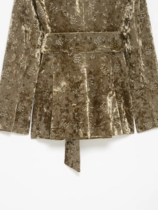 Detailed macro view of bronze metallic velvet fabric texture and white floral patterns