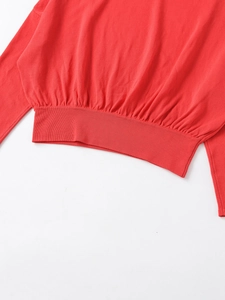 Gros plan sur l'ourlet du pull en maille rouge avec bords-côtes et détails plissés