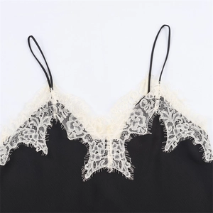 Détail d'un haut en satin noir avec bordure en dentelle florale blanche et fines bretelles
