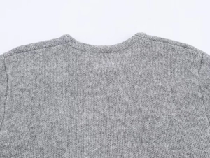 Detailed close-up of gray knitted cardigan neckline and fine shoulder stitching texture