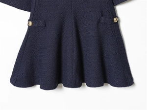 Detail of dark blue tweed dress featuring textured fabric and gold button pockets