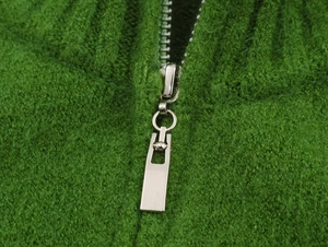 Close-up of sleek silver rectangular zipper on soft green fuzzy knit cardigan jacket