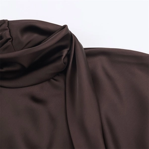 Detail of chocolate satin mini dress featuring a cowl neck and silky draped texture