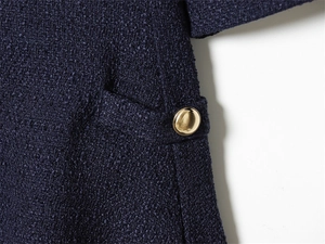Detailed view of navy tweed fabric texture with a premium gold metal button accent