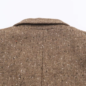 Gros plan sur un blazer marron en tweed à chevrons montrant la texture de laine premium