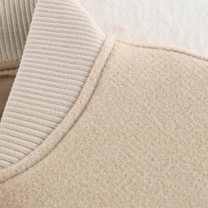 Close-up of oatmeal wool jacket with ribbed knit collar and textured warm fabric