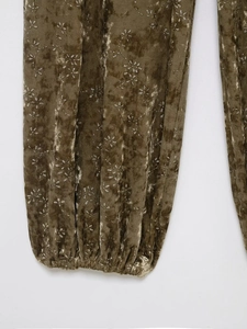 Detailed close-up of velvet trouser cuffs featuring floral prints and elastic ankles